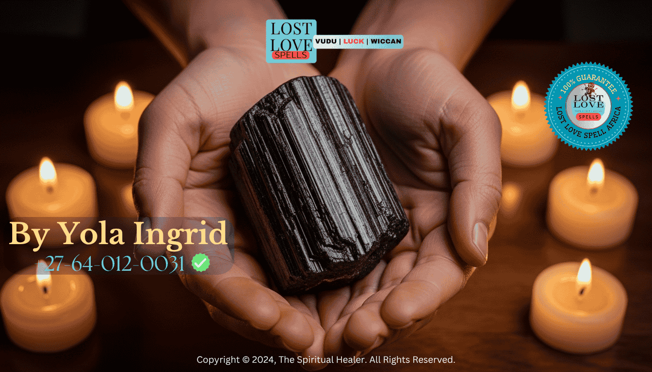 Hands holding a black tourmaline stone surrounded by candlelight for energy protection.